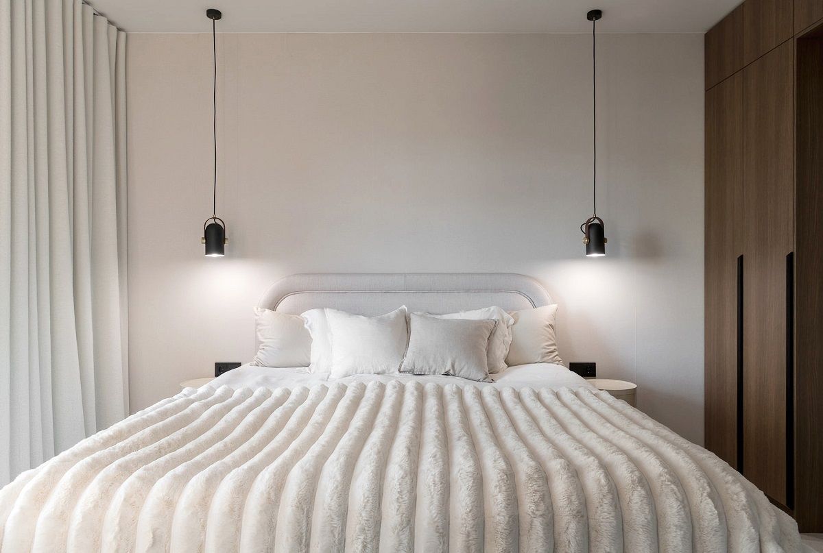 The black pendant lights in the bedroom are placed on both sides of the bed